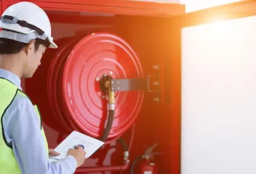 Técnico con casco inspecciona un gabinete contra incendio con manguera y extintor
